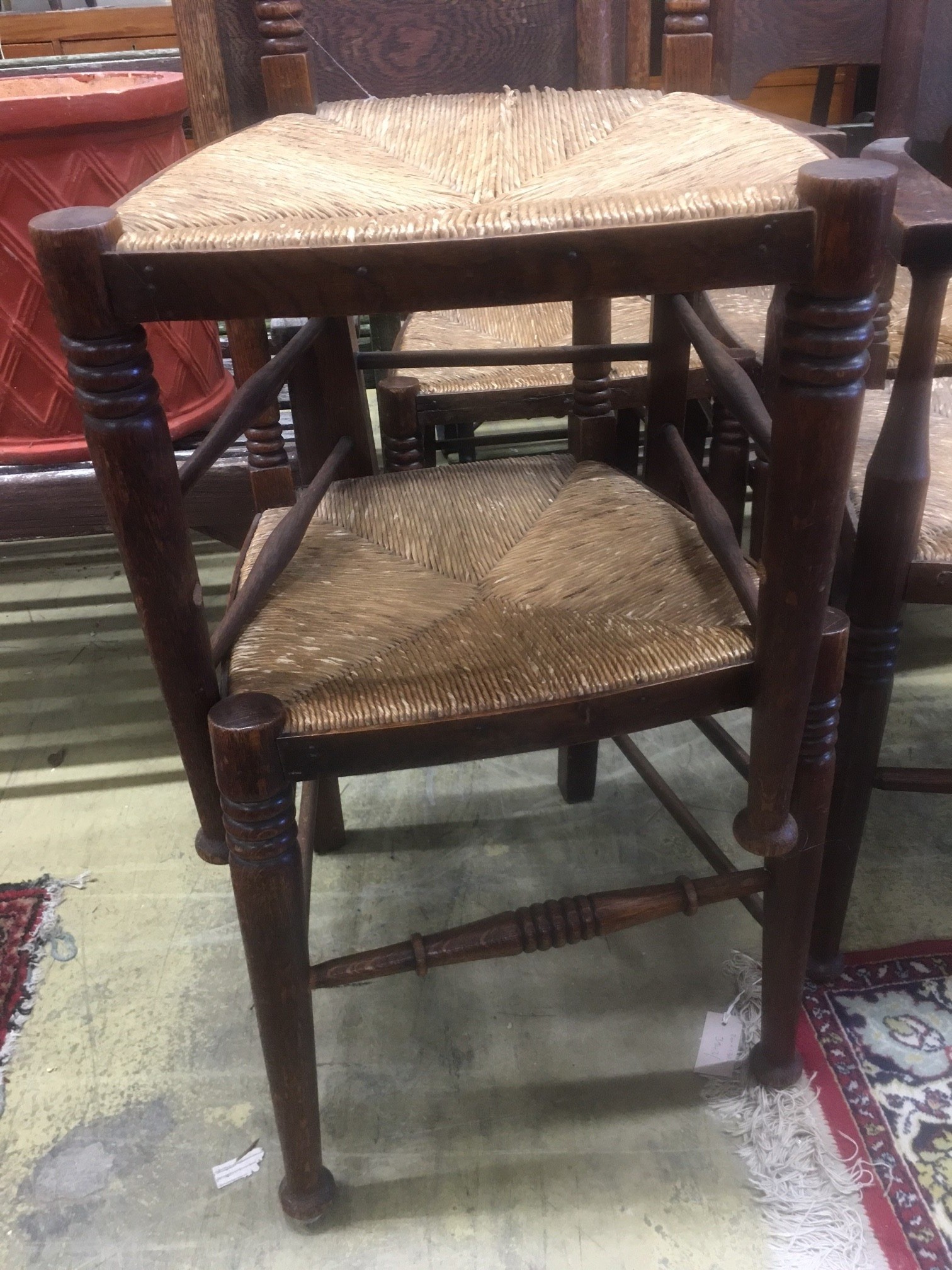 A set of six Arts & Crafts oak chairs, including a pair of carvers, in the Glasgow School manner by William Birch, High Wycombe, with shaped panels backs, ring turned frames and rush seats, carvers W.58cm D.54cm H.109cm